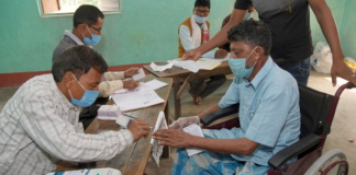 Polling official administering indelible ink to a divyang voter, at a polling booth, during the first phase of the Assam Assembly Election, at Dhekiajuli, in Sonitpur district, Assam on March 27, 2021